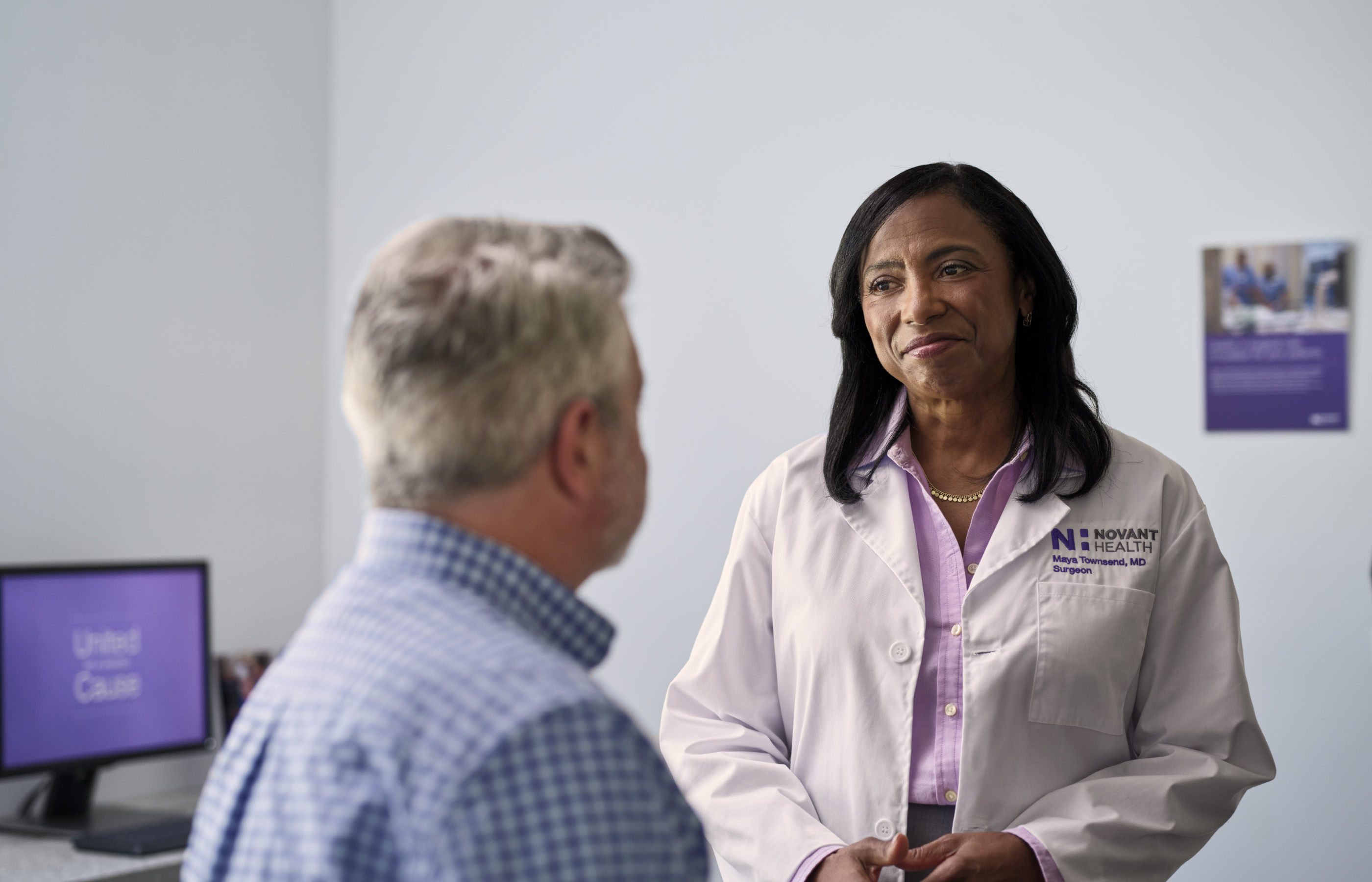 Dr. Maya Townsend is talking with a male patient during an office visit. Dr. Maya Townsend is talking with a male patient during an office visit.