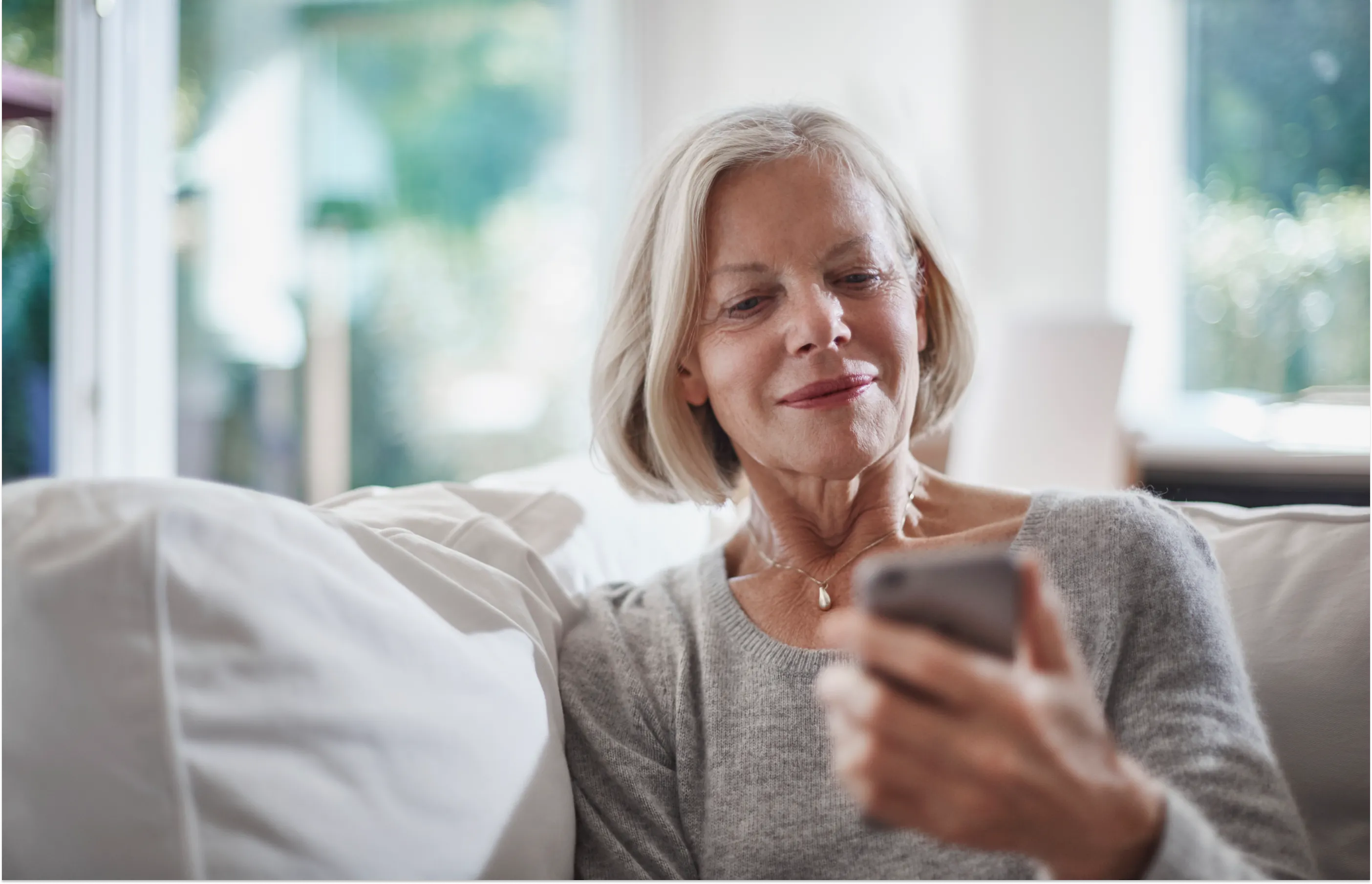 Senior woman checking a smartphone while sitting on a couch