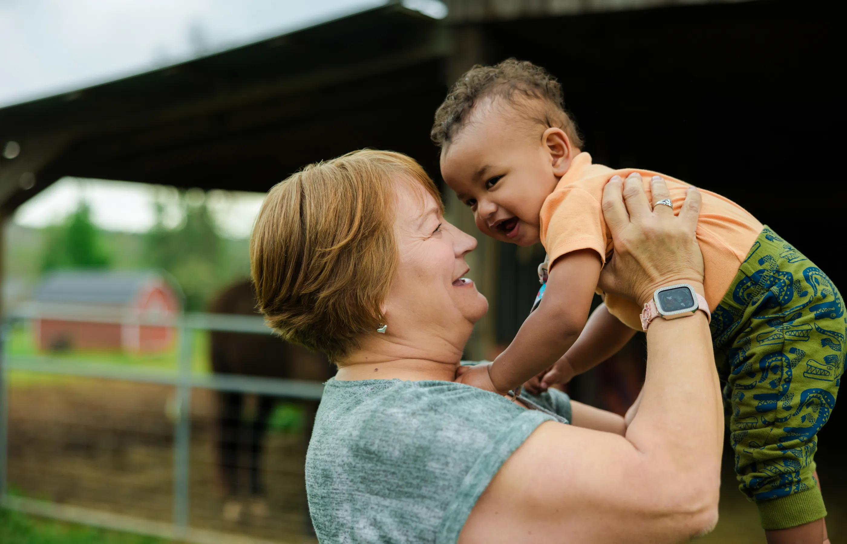 Woman holding up a baby boy on a farm