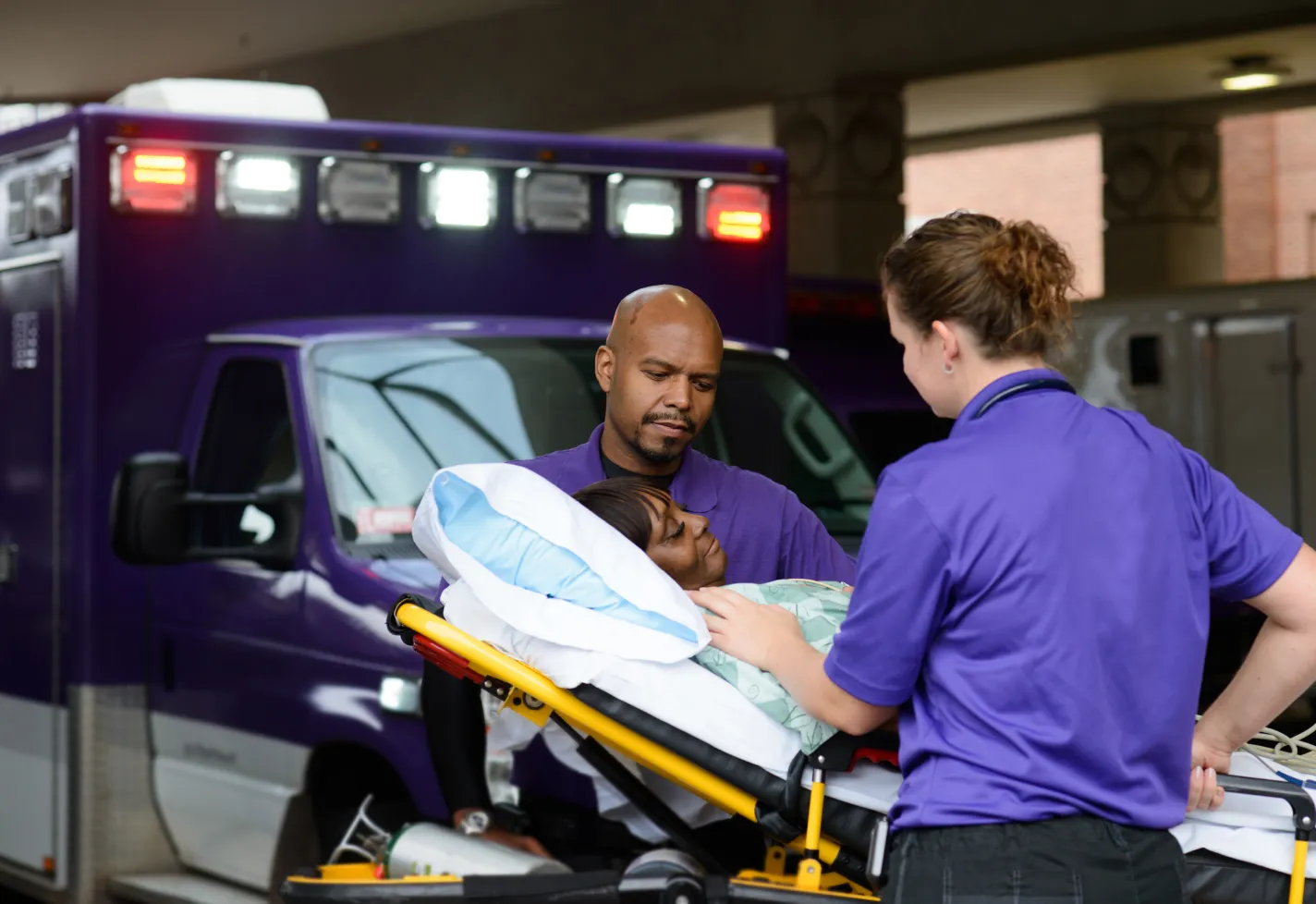 Two Novant Health team members are wheeling a patient on a stretcher. 