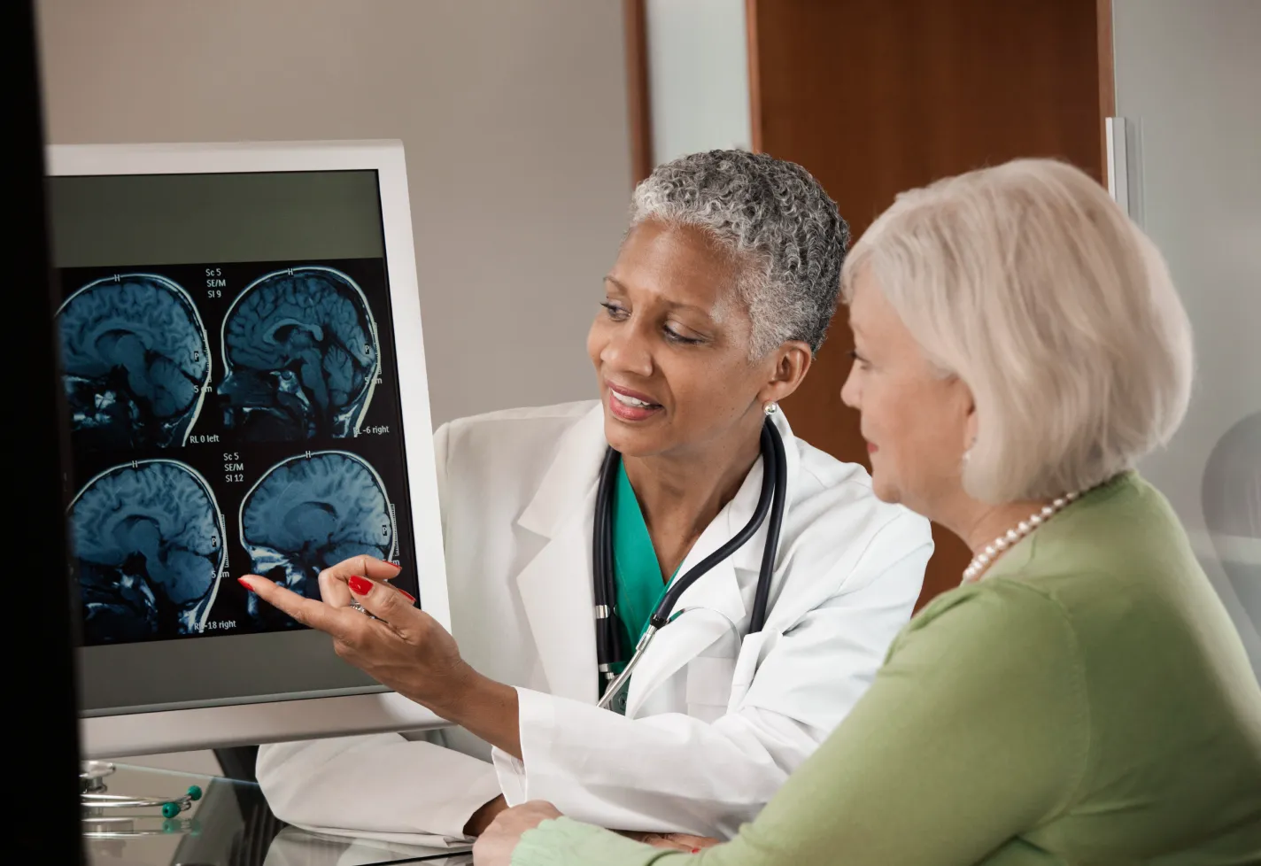 Physician and a senior woman view a brain imaging screen