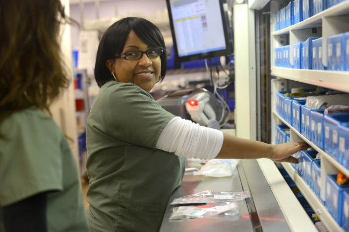 A Novant Health team member is talking with a co-worker as they organize medications.