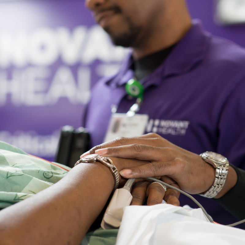 A Novant Health team member is holding the hand of an emergency trauma patient as they transport them.