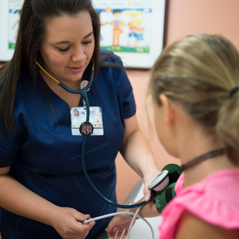 A Novant Health nurse is taking a young girls blood pressure. 