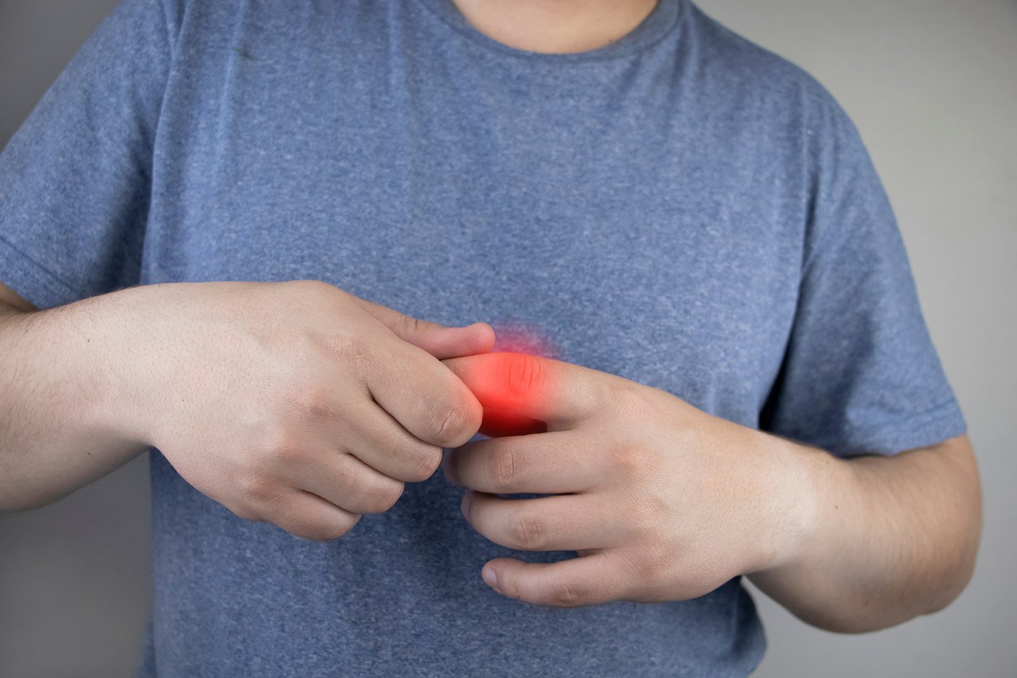 Man holding his finger which is swollen and in pain from a finger sprain