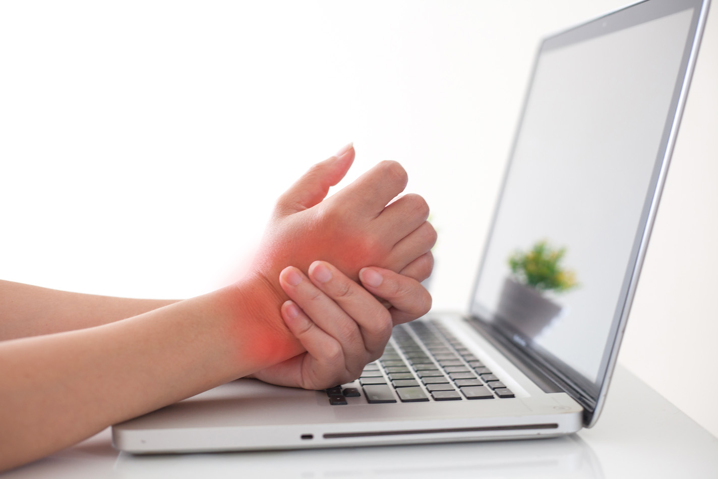 Woman at her laptop holding her wrist due to tendonitis pain